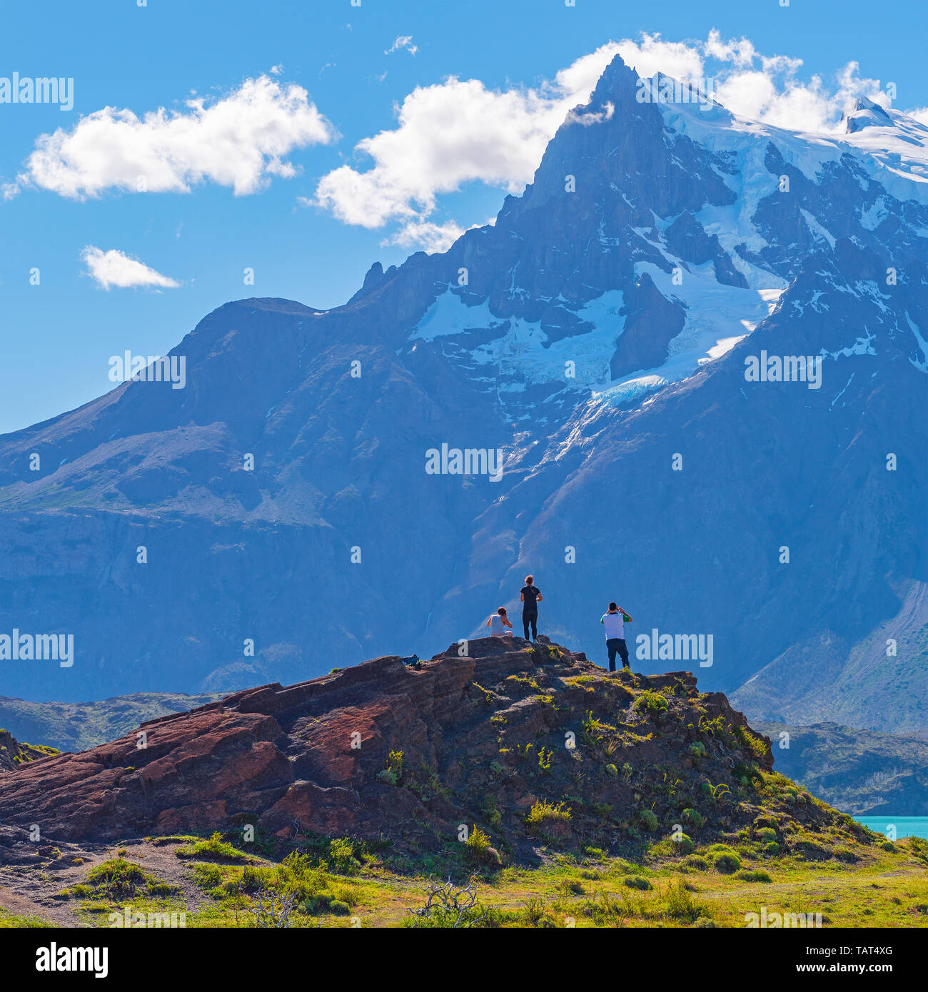 Square photograph of young tourists looking upon Pehoe Lake and the Andes peaks of Torres del Paine national park, Patagonia, Chile. Stock Photo