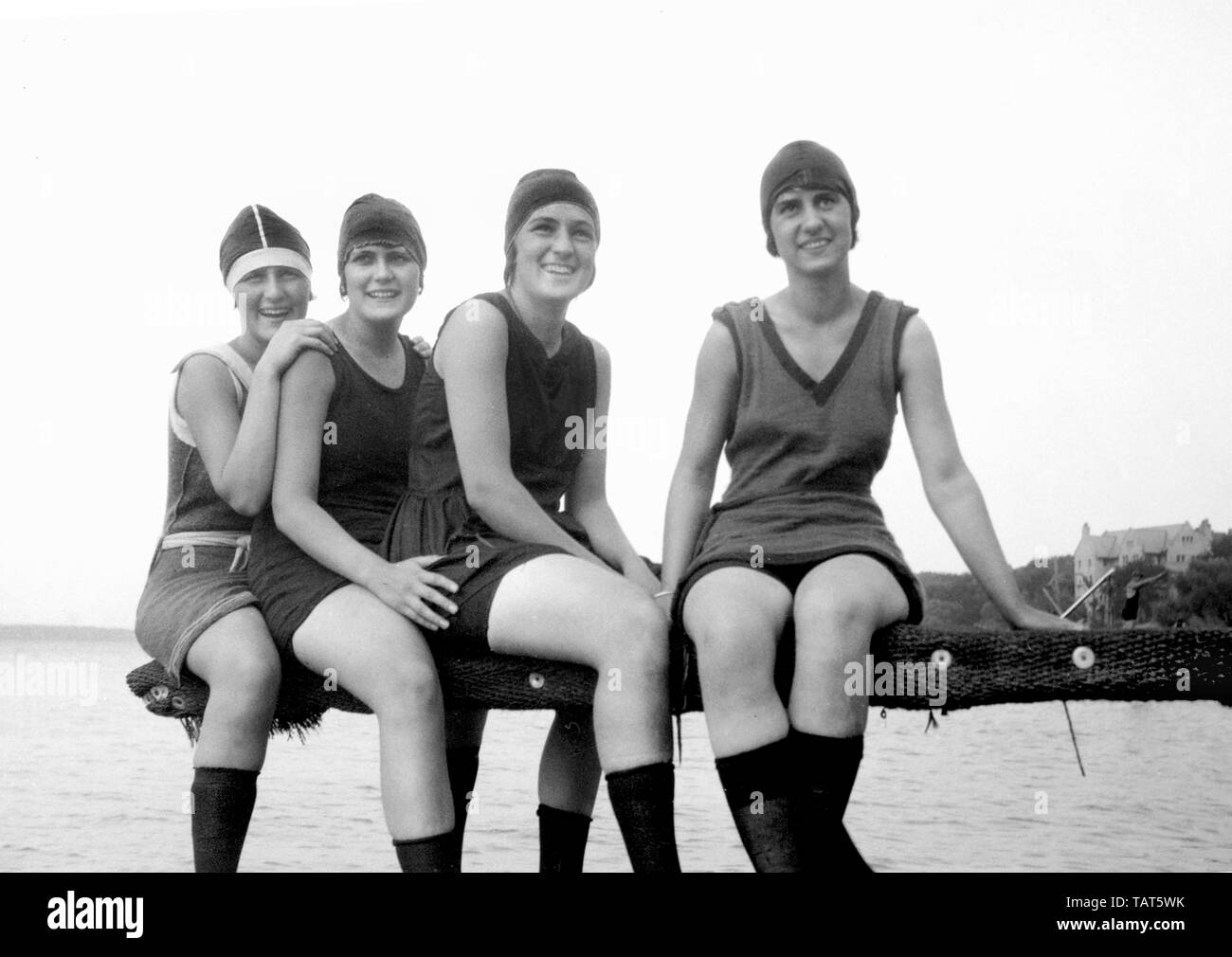 A group of young women happily pose on a diving board overlooking Lake