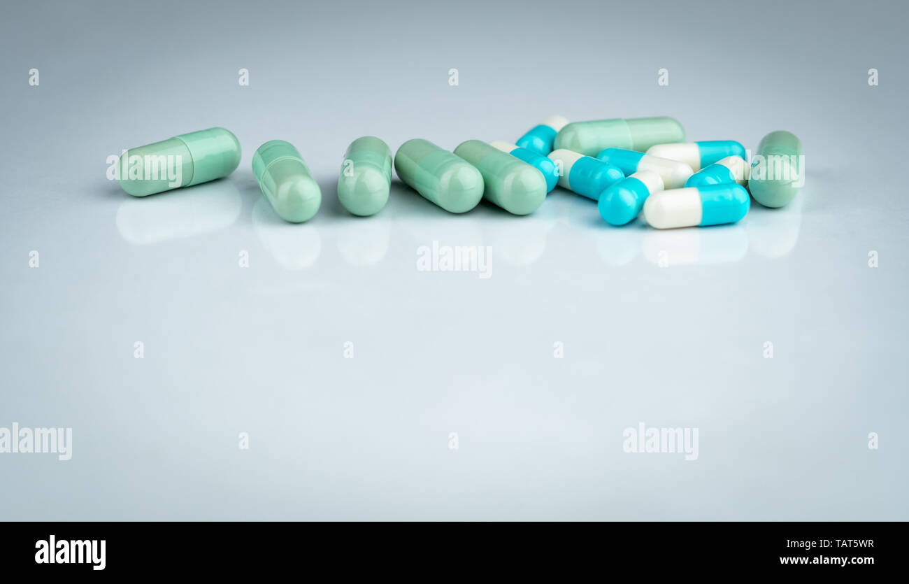 Herbal and drug interactions. Green and blue capsule pill on white