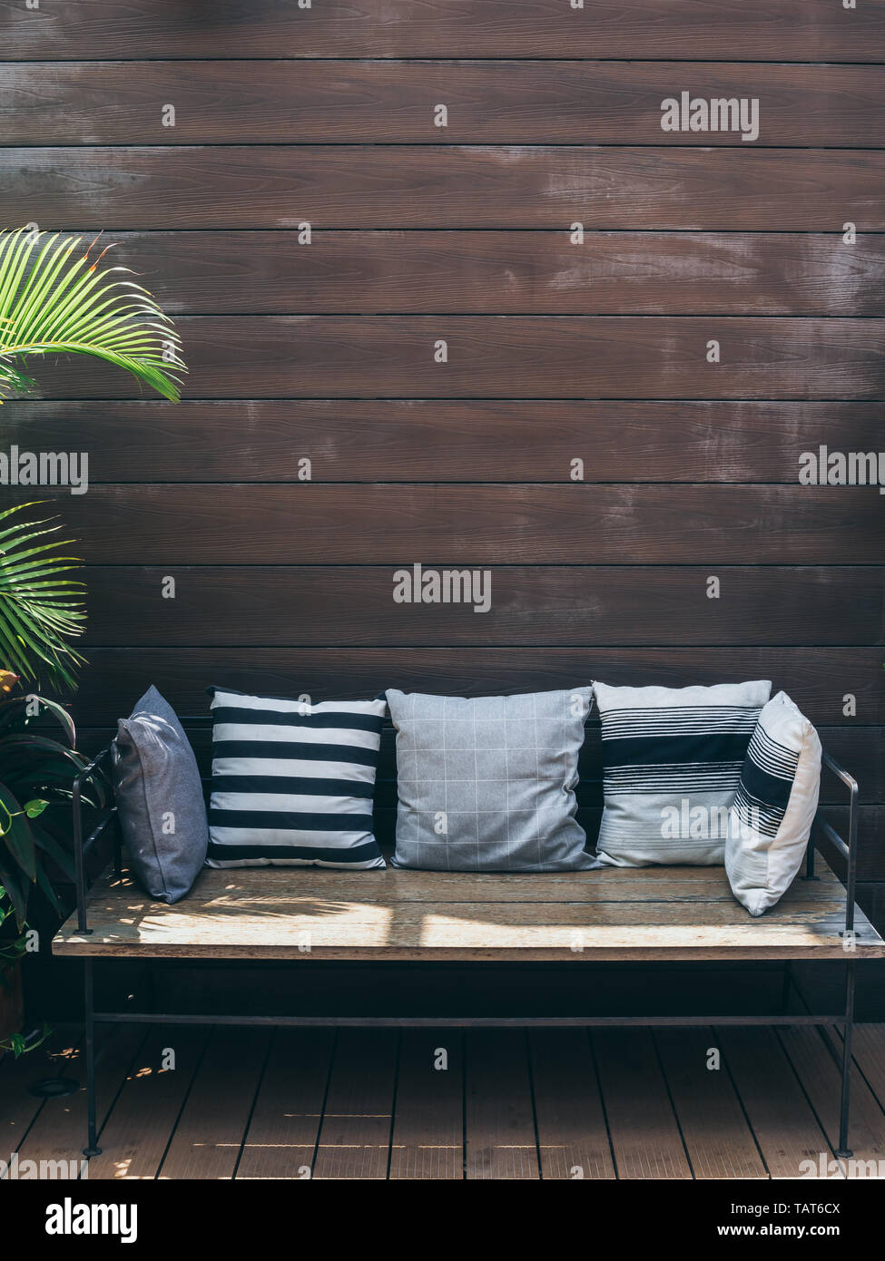 Wooden Sofa With Pillows With Green Tropical Palm Leaves On Wooden