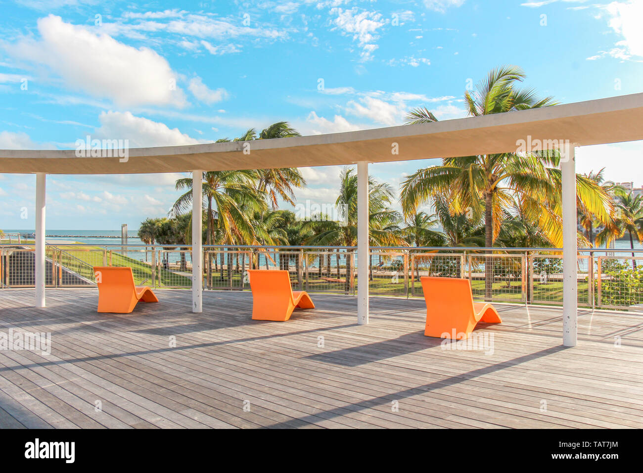 Three orange lounge chairs overlooking South Pointe Park in Miami Beach, Florida, USA. Stock Photo