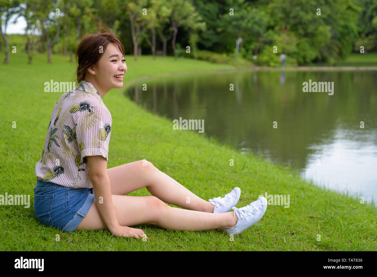 Young beautiful Asian tourist woman relaxing at the park Stock Photo