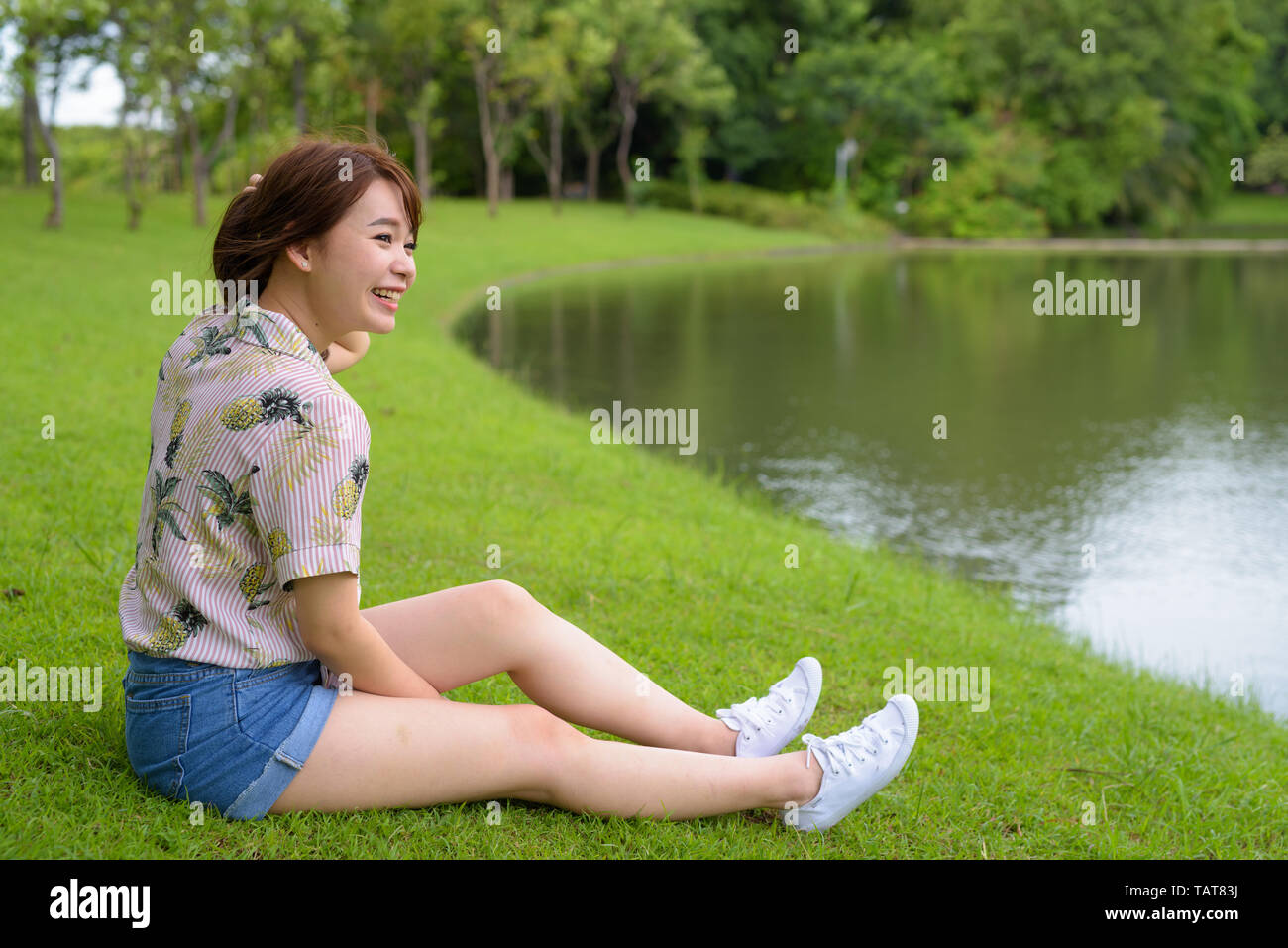 Young beautiful Asian tourist woman relaxing at the park Stock Photo