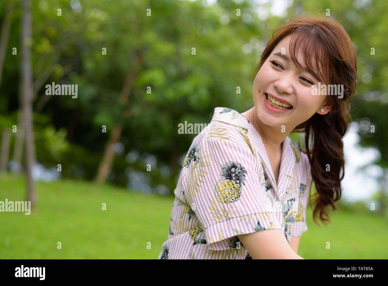 Young beautiful Asian tourist woman relaxing at the park Stock Photo