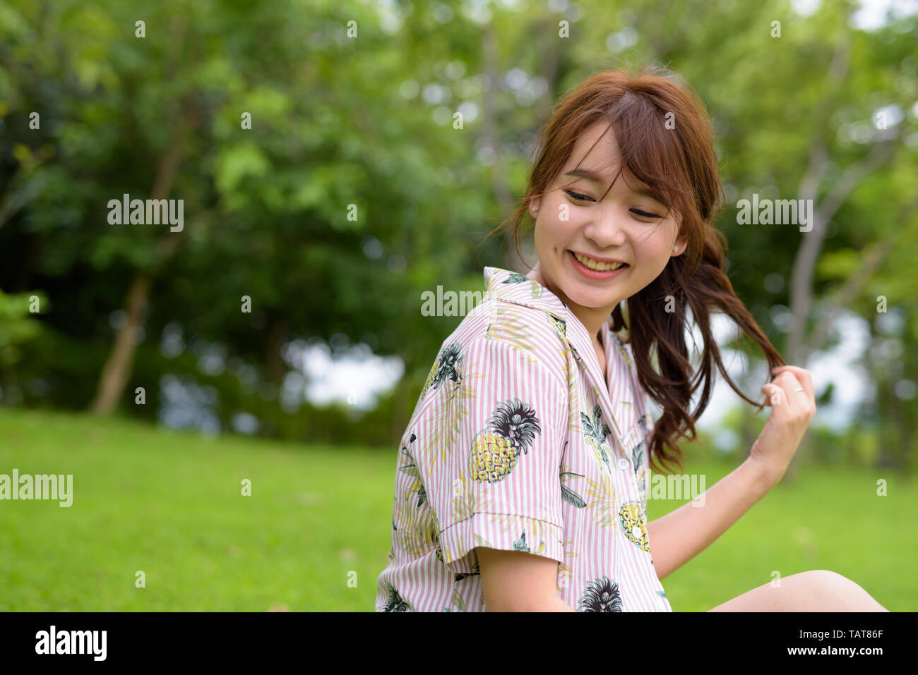 Young beautiful Asian tourist woman relaxing at the park Stock Photo