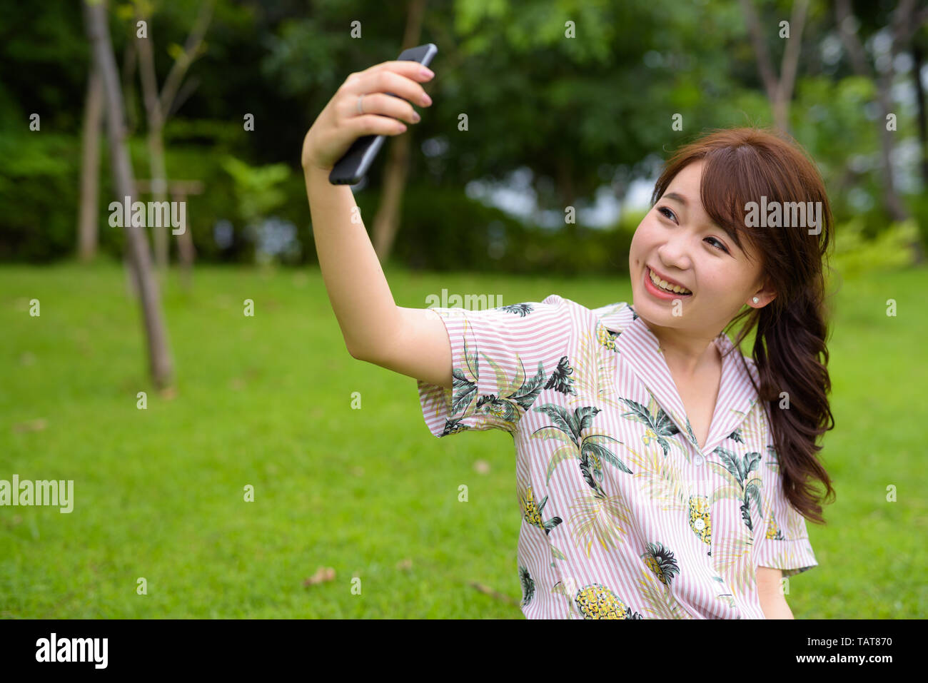 Young beautiful Asian tourist woman relaxing at the park Stock Photo