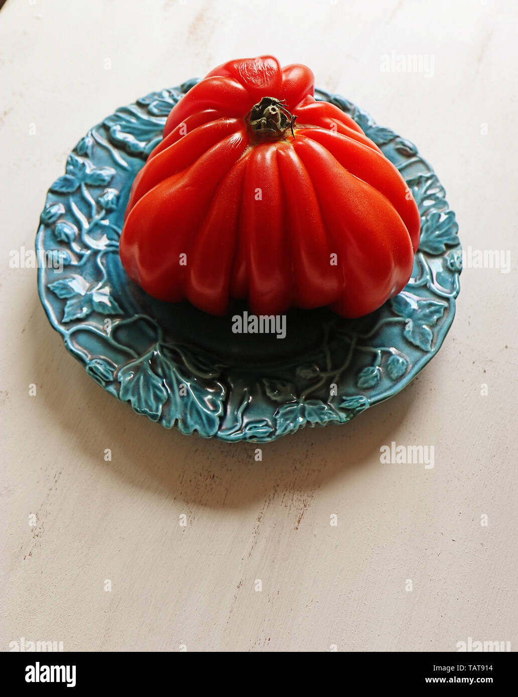 Giant beef heart tomato on a blue plate Stock Photo