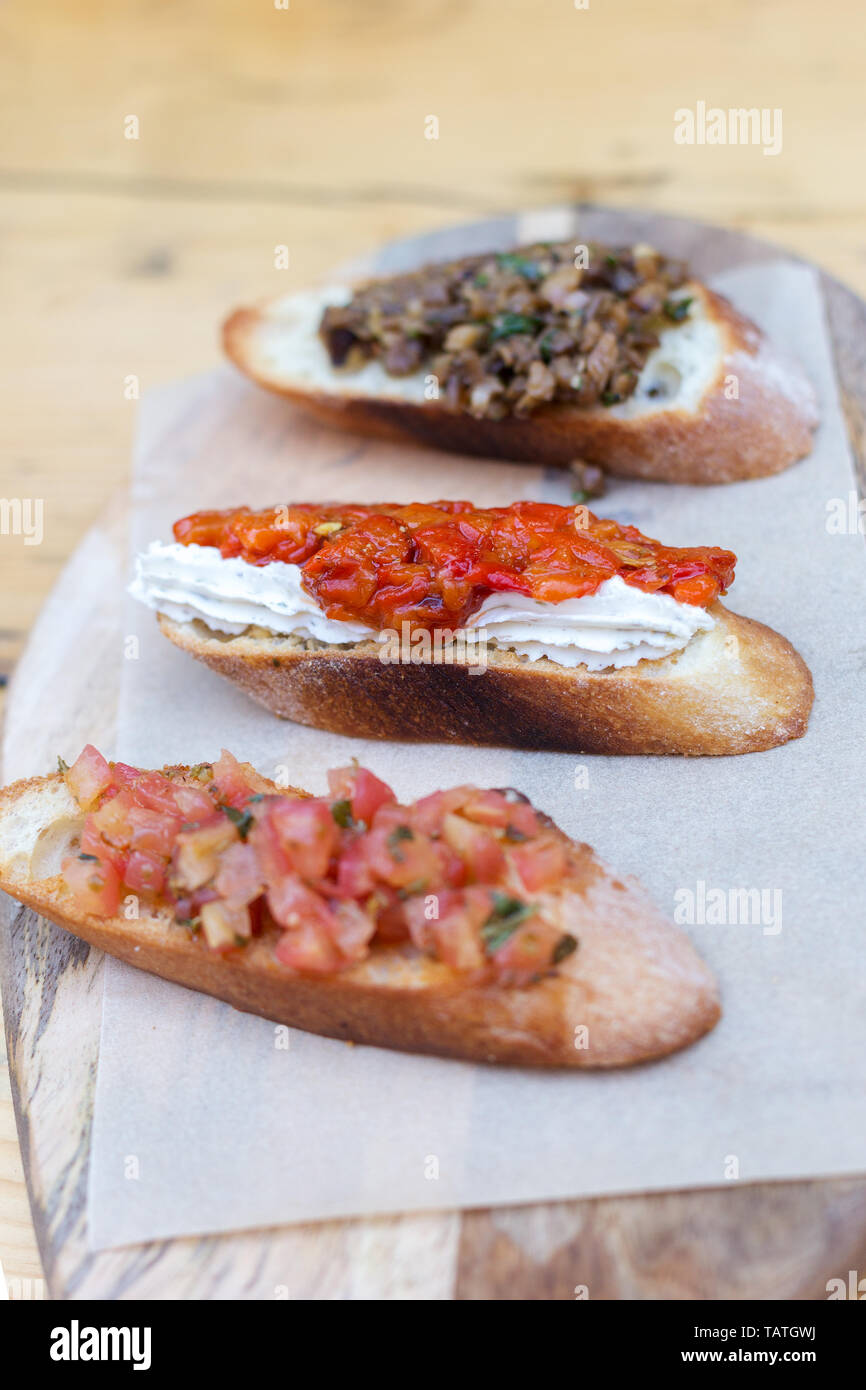 Bruschetta with tomatoes and herbs on craft paper on wood board. Concept of Italian food Stock Photo