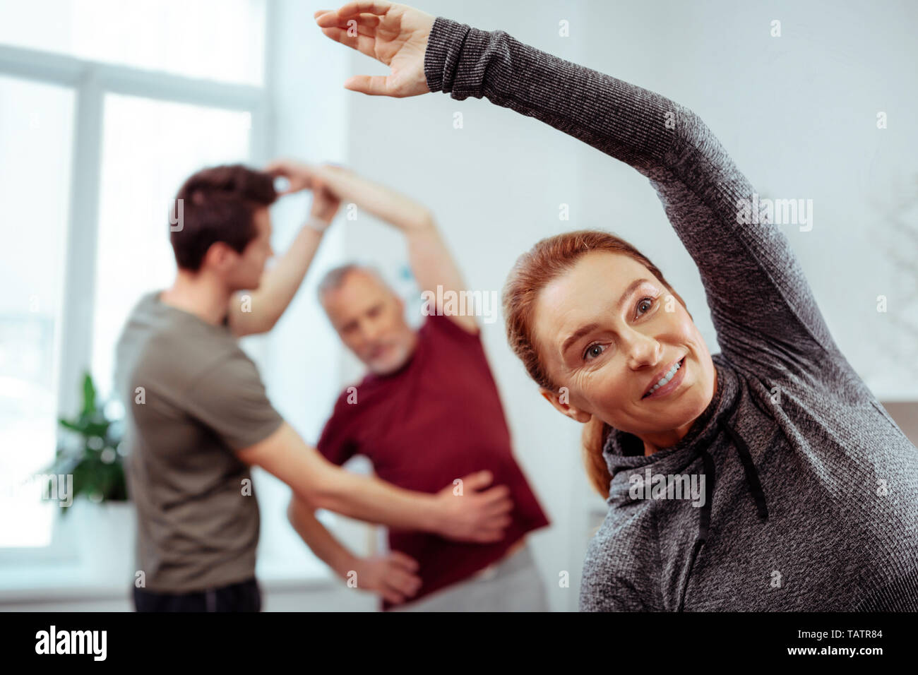 Physical activity. Joyful positive woman raising her hand up while doing physical exercises Stock Photo
