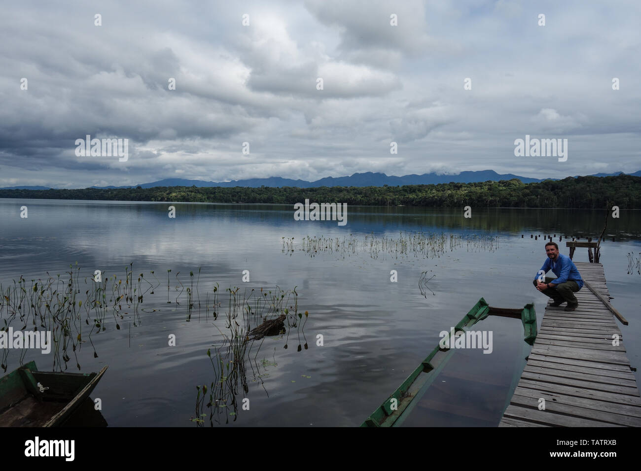 Backpacker in front of secret lake with a lot of water plants and piranhas and water reflections of the blue, cloudy sky in the Madidi Jungle, Boliva Stock Photo