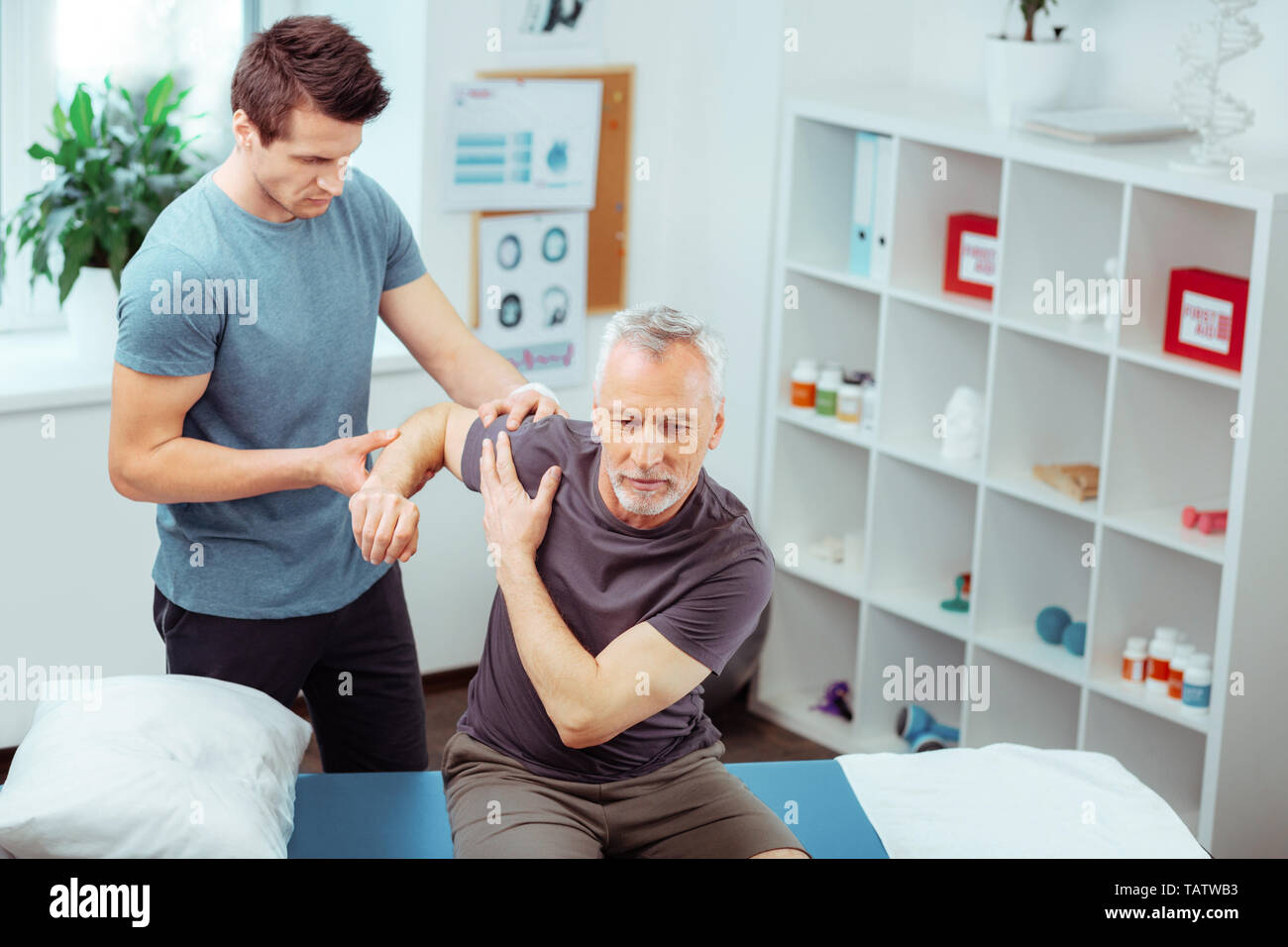Rehabilitation centre. Top view of a pleasant aged man raising his hand ...