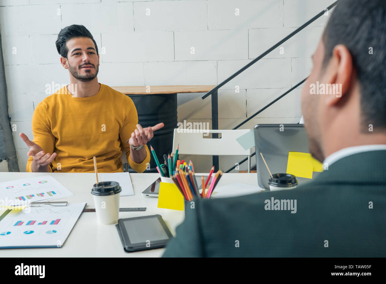A young man is interviewed for a job. Guy's talking to his boss in the office. Business communication. Stock Photo