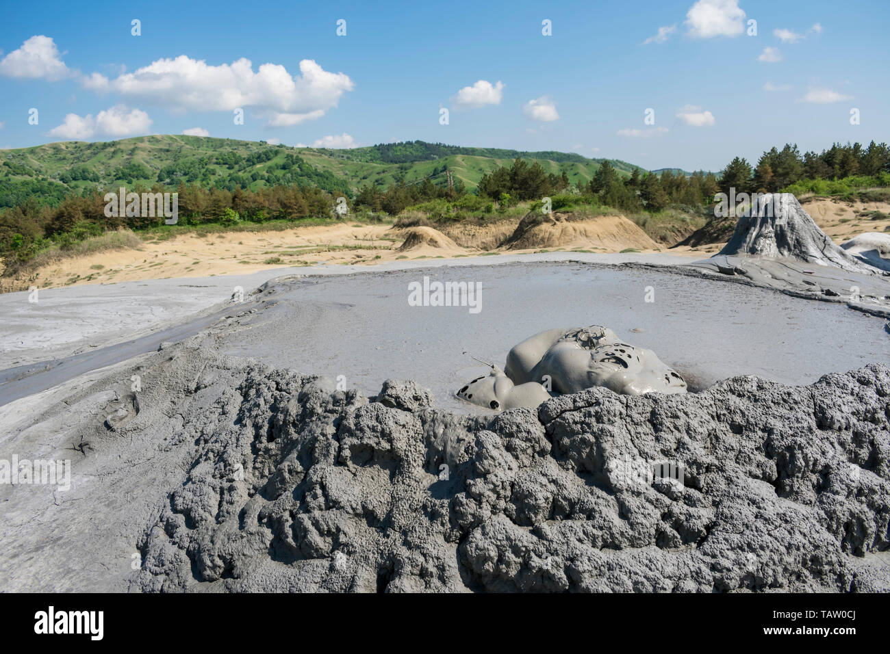 The muddy volcanoes from Buzau , Romania are a geological surface phenomenon in which warm flow of mud erupts on the ground , expelling gases Stock Photo