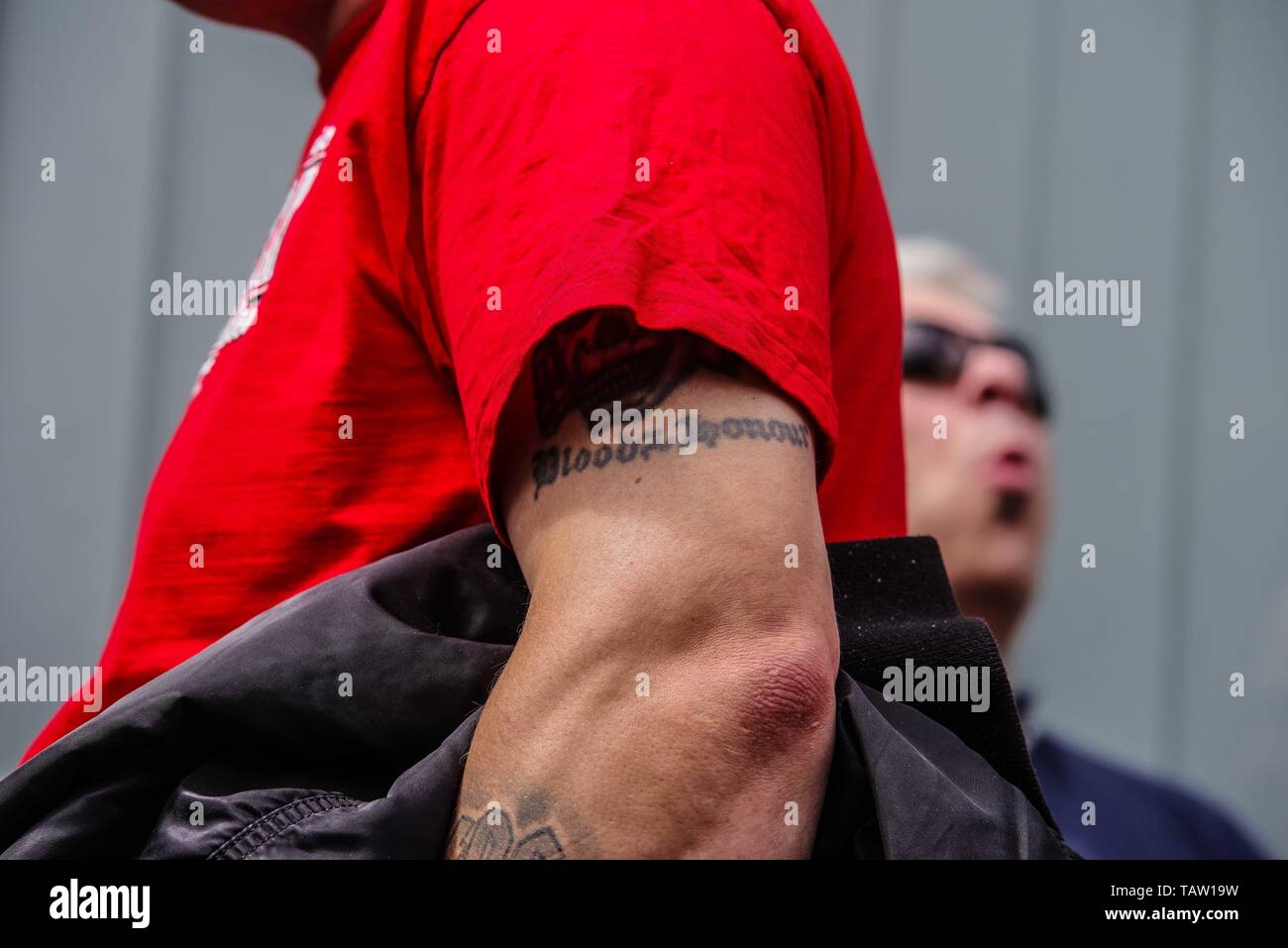 Dortmund, Nordrhein Westfalen, Germany. 25th May, 2019. A neonazi at an event in Dortmund displays a portion of a ''Blood and Honour'' tattoo, denoting membership to this banned terror group, as well as an illegal Totenkopf. Prior to the European Elections, the neonazi party Die Rechte (The Right) organized a rally in the German city of Dortmund to promote their candidate, the incarcerated Holocaust denier Ursula Haverbeck. The demonstration and march were organized by prominent local political figure and neonazi activist Michael Brueck (Michael BrÃ¼ck) who enlisted the help of not only Germ Stock Photo