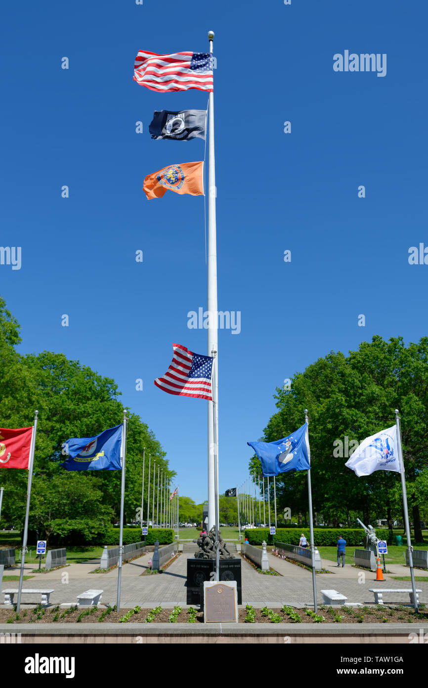East Meadow, New York, USA. 25th May, 2019. Flaying from a tall flagpole are, from top to bottom, the American Flag, the POW-MIA flag, and the Nassau County State of New York flag. It's surrounded by shorter flagpoles, each flying a military flag of the United States Armed Forces - Army, Navy, Marine Corps, Air Force, Coast Guard, at the Veterans Memorial Plaza at Eisenhower Park on Long Island. Credit: Ann Parry/ZUMA Wire/Alamy Live News Stock Photo