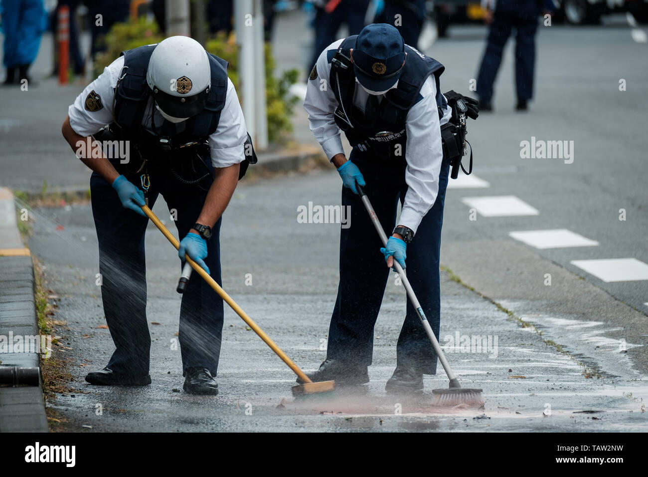 A police officer Kanagawa cleans the road after mass stabbing close to Noborito station on 28, 2019 in Kawasaki, Japan. According to media reports, 16 people, including elementary