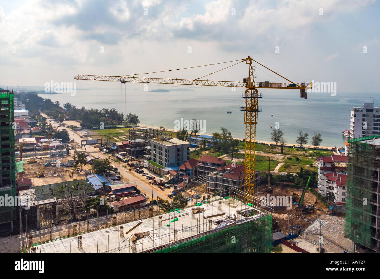 Construction of multi-storey buildings in Cambodia, Sihanoukville . Construction cranes on background of buildings. Storey building against the blue s Stock Photo