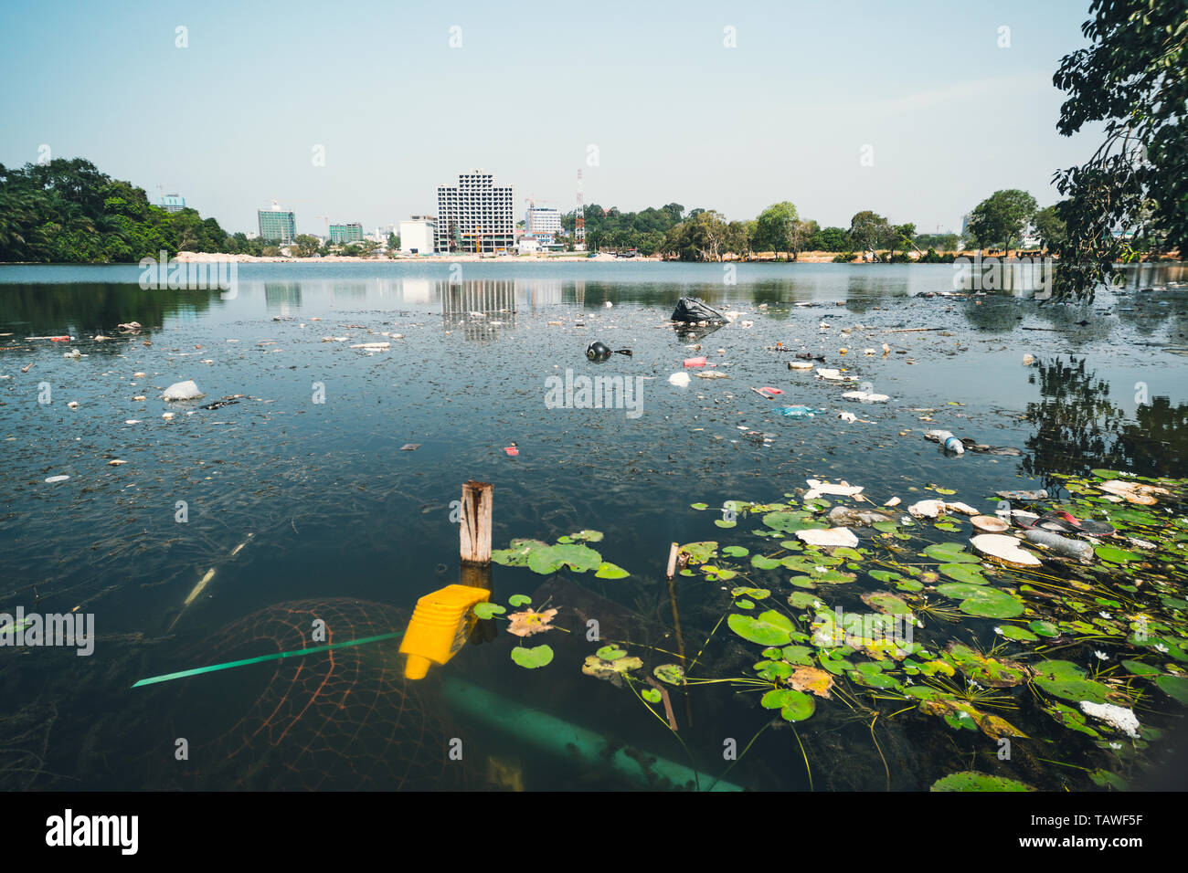 City dump in the pond in the Park. Garbage lies in the water on one of the urban landscape. plastic bottles were thrown into the water. Stock Photo