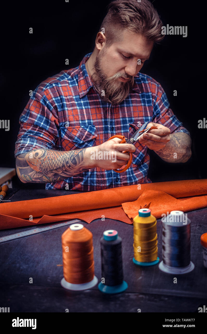 Artist working with leather processing a leather workpiece . Stock Photo
