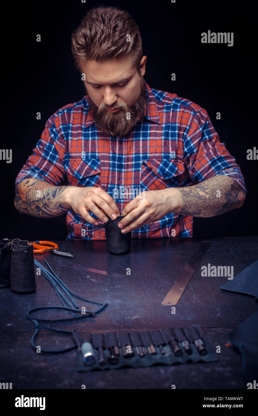 Tanner processes a workpiece from leather at his shop. Stock Photo