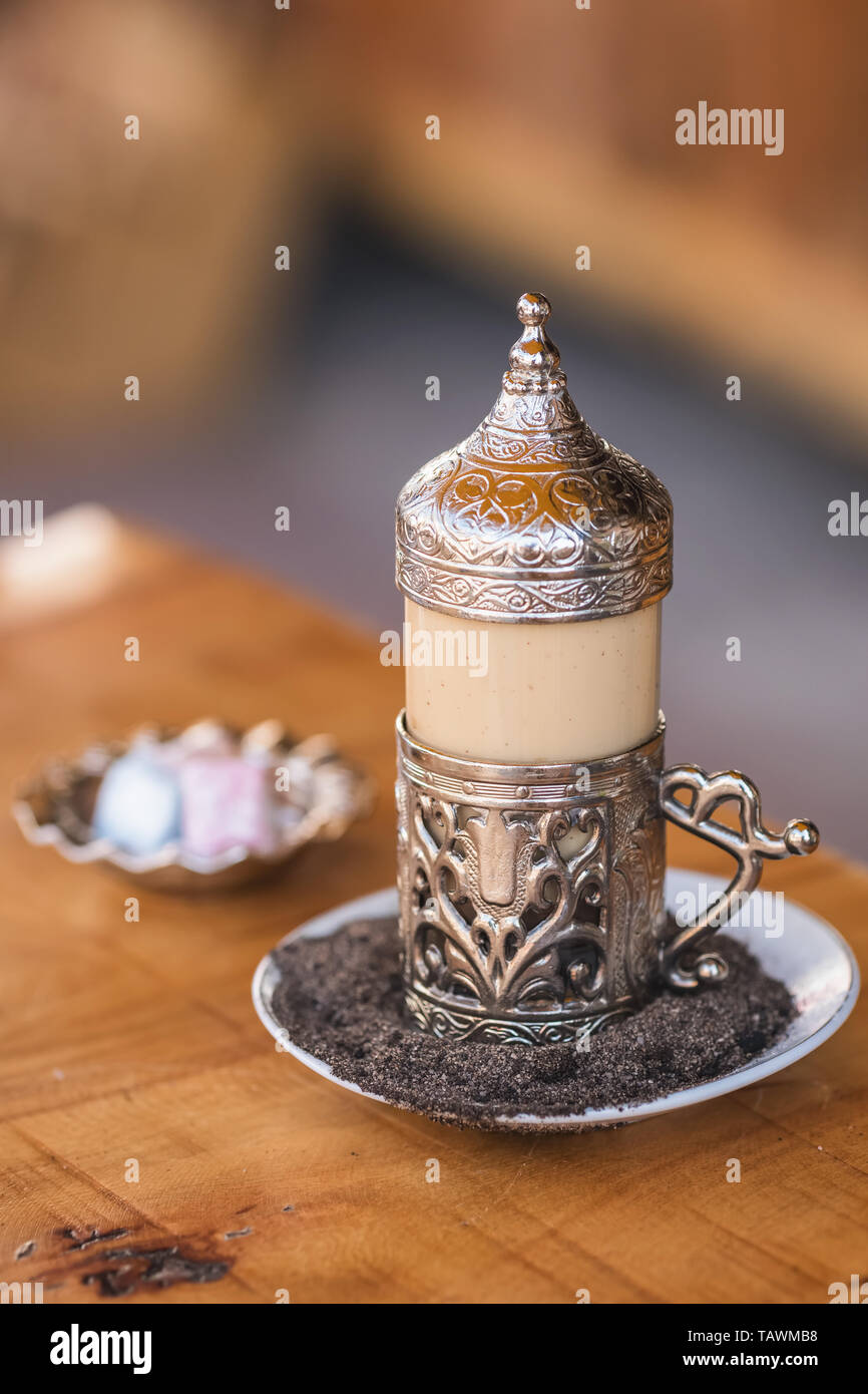 Traditional turkish coffee served in beautiful metal cup on hot sand and turkish delights at background in outdoor cafe in Turkey Stock Photo