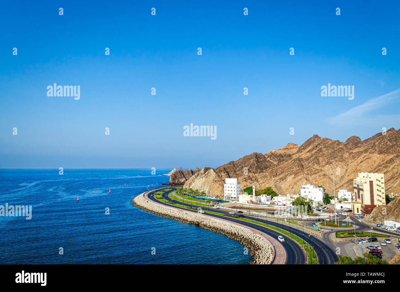 Beautiful landscape of Oman with a curvy seaside road, mountains, blue sky and blue sea. From Muttrah, Muscat. Stock Photo