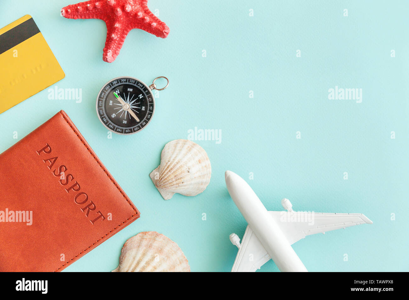 Vacation travel adventure trip concept. Minimal simple flat lay with plane passport compass gold credit card and shell on blue pastel colourful trendy Stock Photo