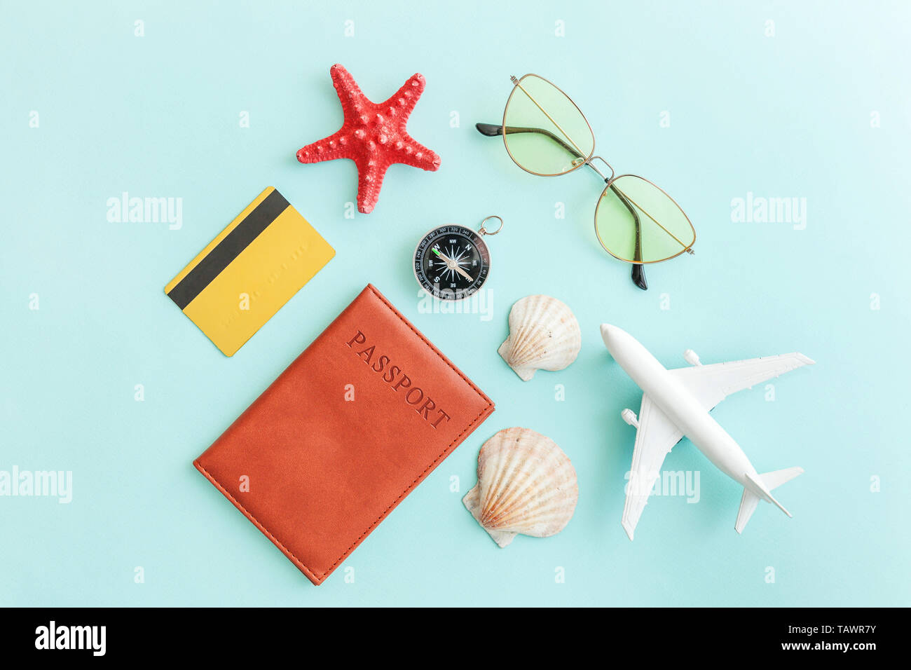 Vacation travel adventure trip concept. Minimal simple flat lay with plane passport sunglasses compass gold credit card shell on blue pastel colourful Stock Photo