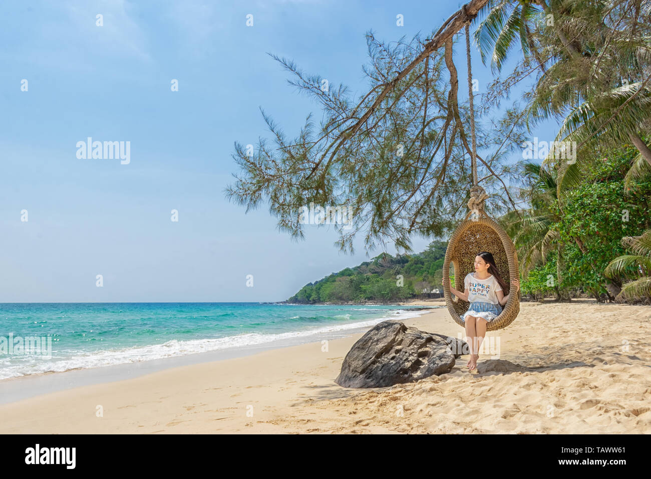 happy traveler Asian woman relaxing on luxury swing and looking beautiful nature landscape beach. summer holiday vacation travel trip concept Stock Photo