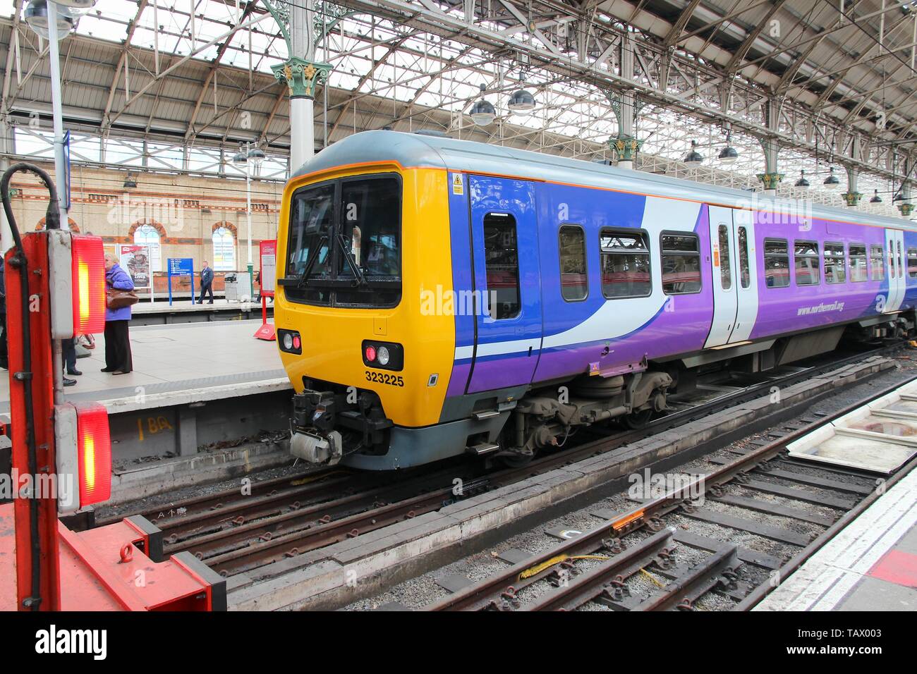 MANCHESTER, UK - APRIL 23, 2013: People walk by Northern Rail train in Manchester, UK. NR is part of Serco-Abellio joint venture. NR has fleet of 313  Stock Photo