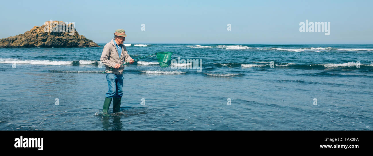 Volunteer taking garbage out of the sea Stock Photo