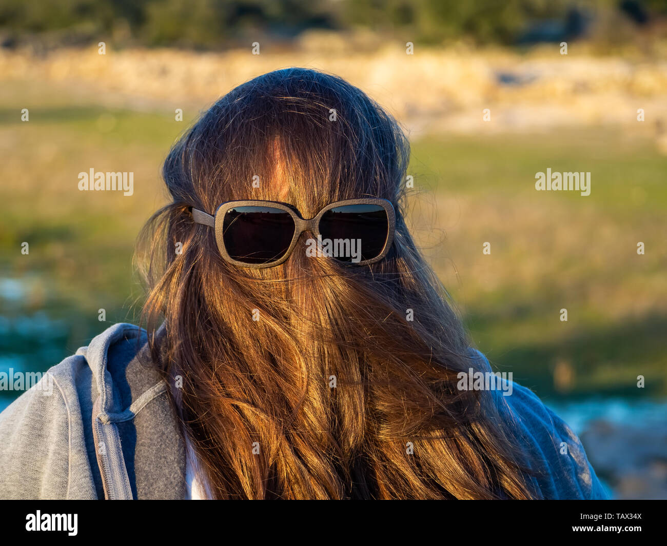 A curvy woman making funny gestures with hair in front of his face and sunglasses Stock Photo