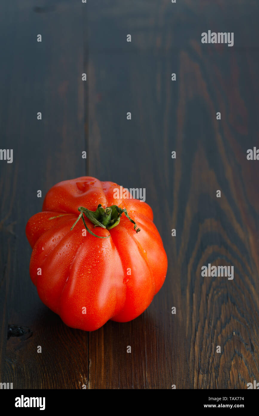 Large freshly harvested oxheart tomato. Dark wooden table, high resolution, negative space Stock Photo