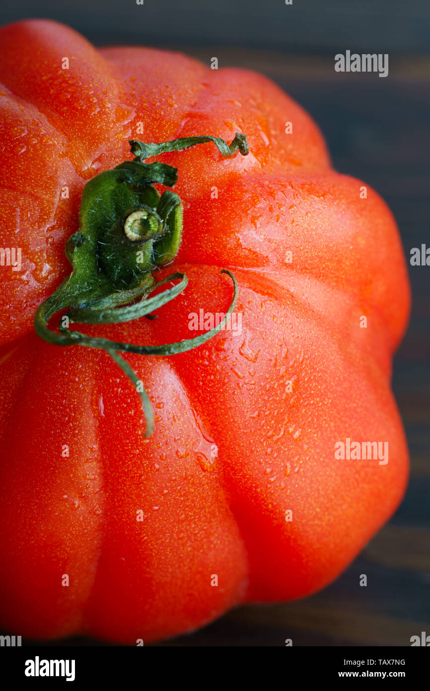Macro shot of a freshly harvested oxheart tomato. Dark wooden table, high resolution Stock Photo