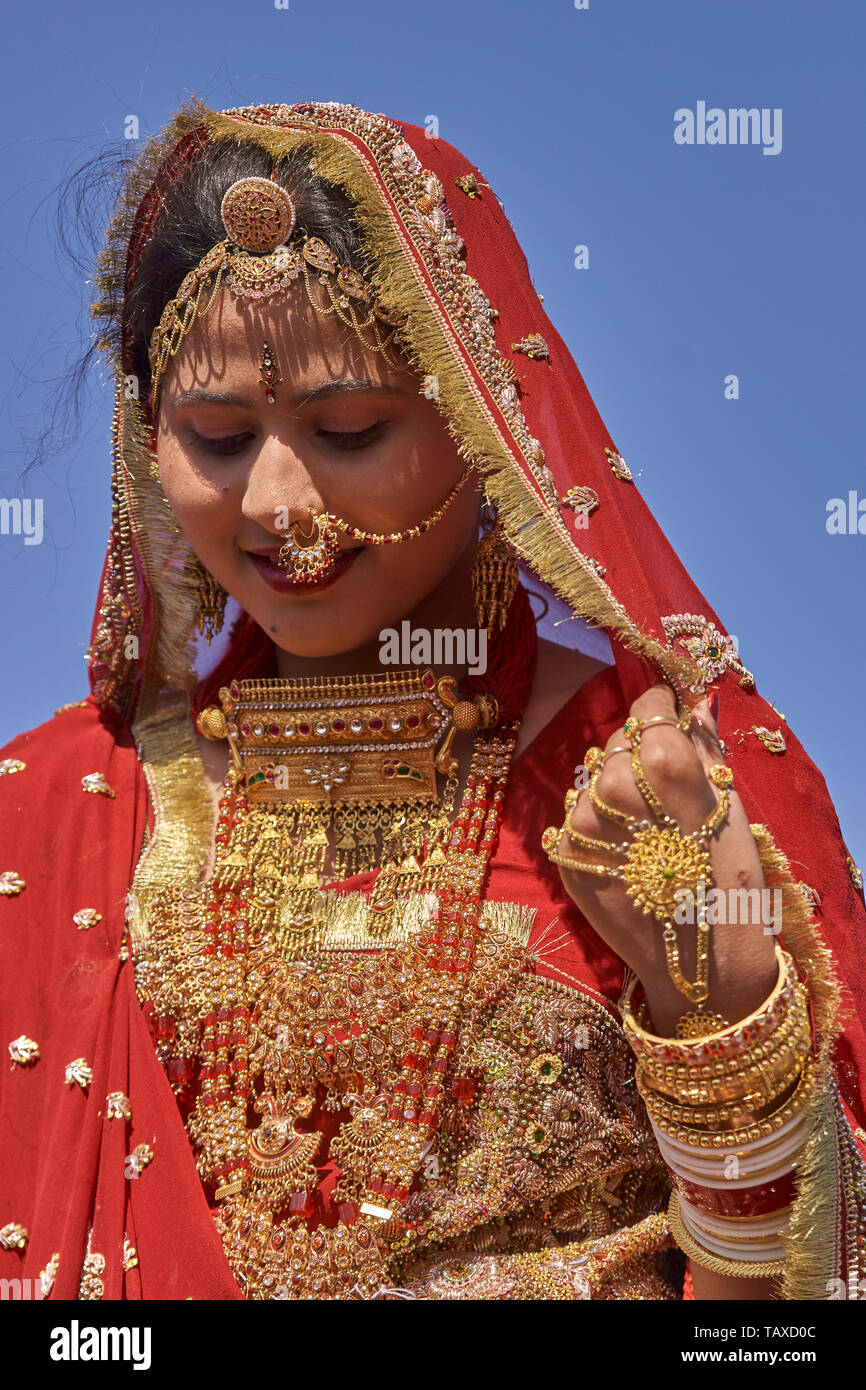 Indian lady dressed in ornate red sari and adorned with ...