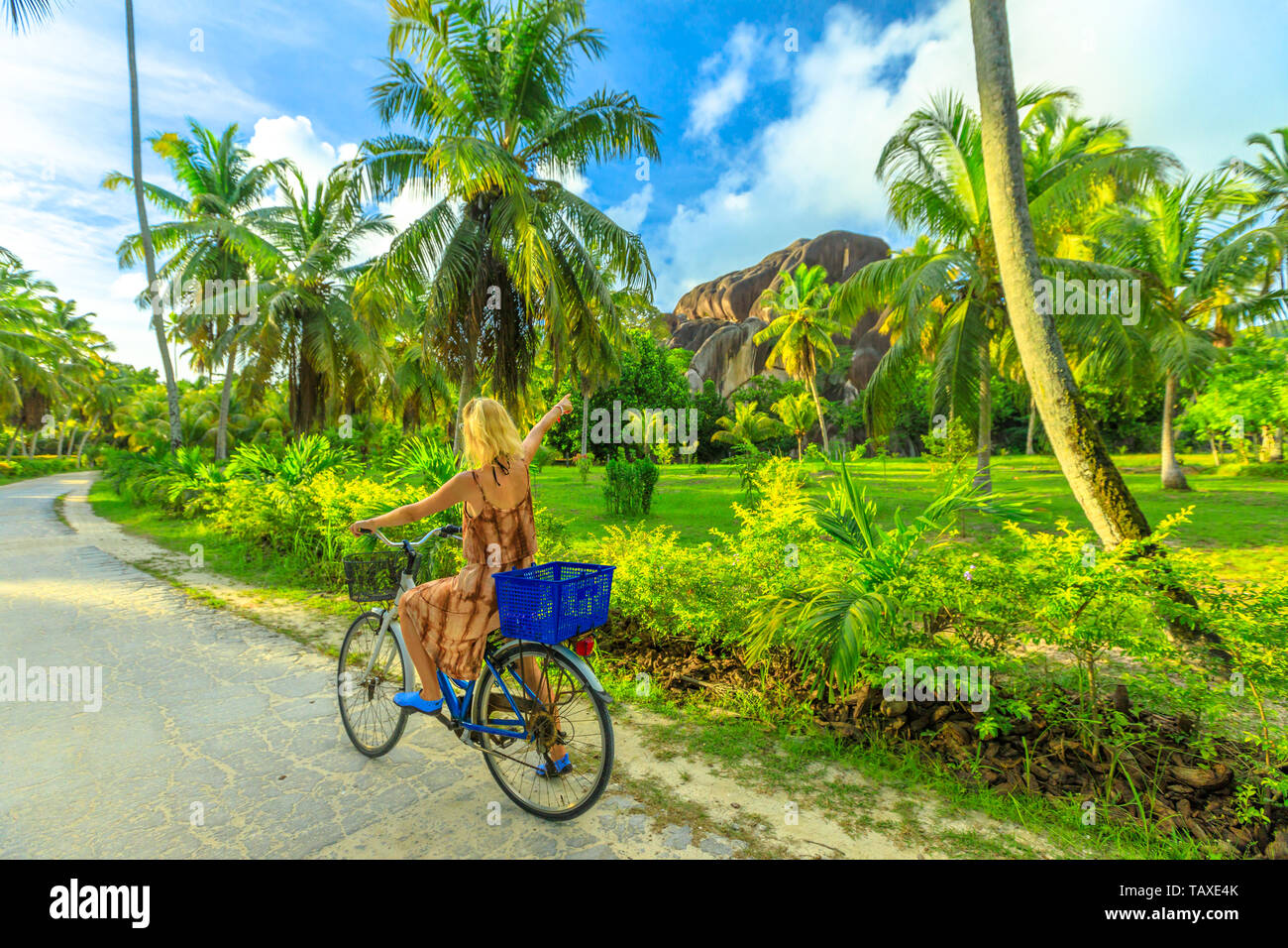 La Digue, Seychelles. Tourist woman on bicycle pointed Giant Union Rock, a monolith at Union Estate a former coconut and vanilla plantation near Anse Stock Photo