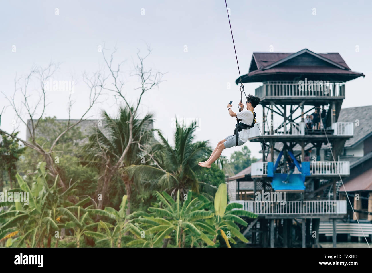 A Male Tourist Flying On A Zipline Aka Flying Fox Across The Lake A Male Tourist Flying On A Zipline Aka Flying Fox Across The Lake