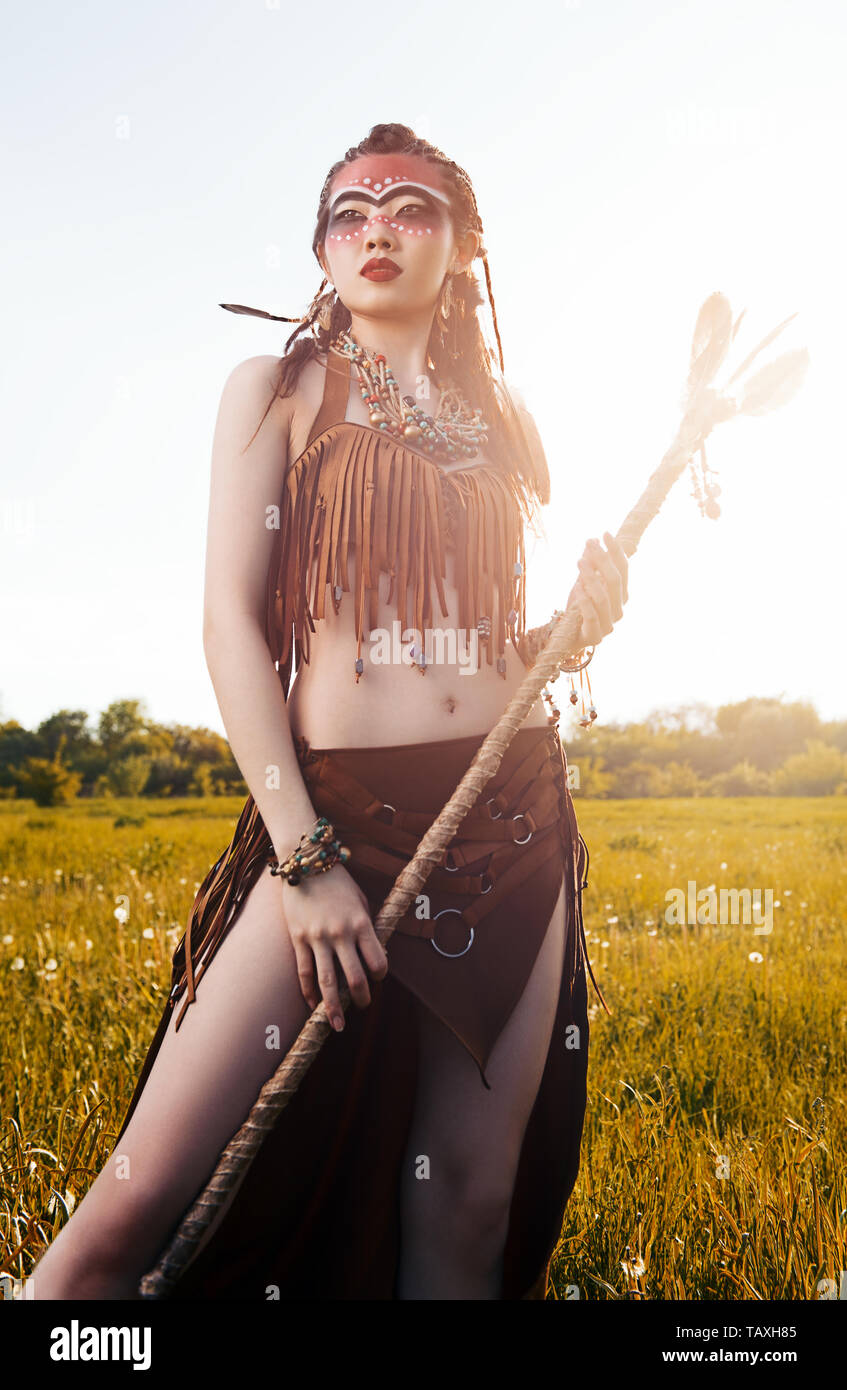 Outdoor portrait of the pretty young shamaness (witch doctor) with staff. Lovely shaman (sorceress) in the field Stock Photo