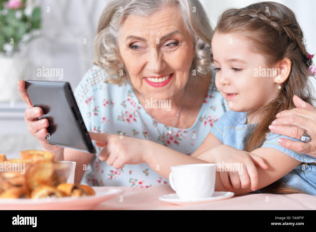 Cute little girl with her grandmother looking at tablet Stock Photo - Alamy