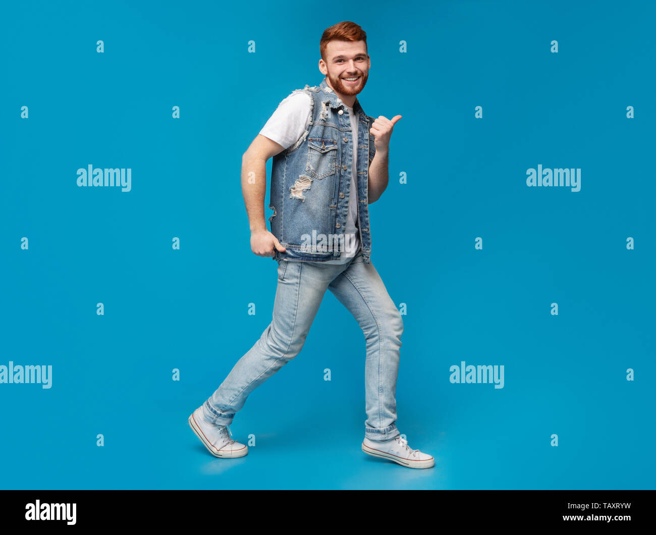 Cool millennial man dancing with thumbs up gestures in studio Stock Photo