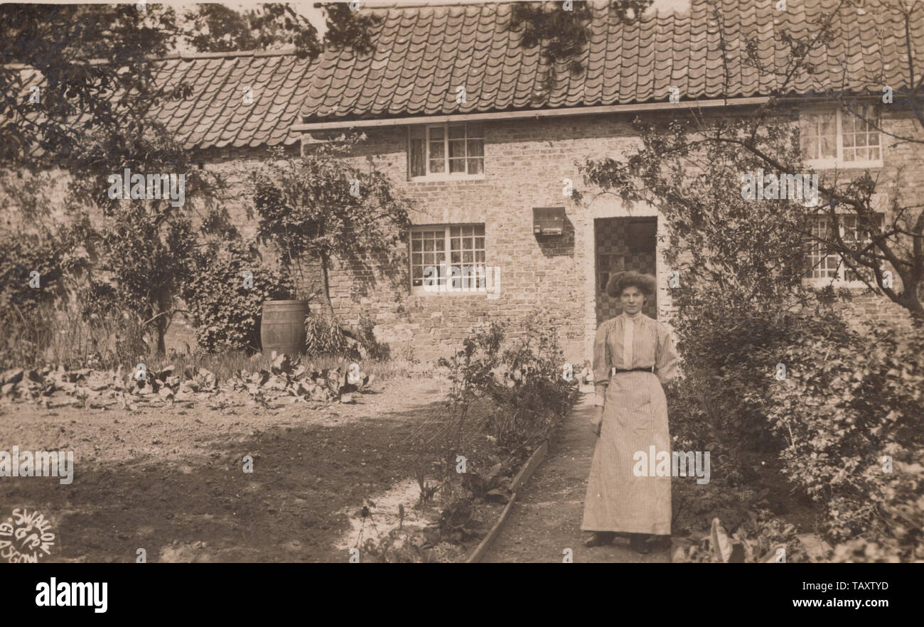 Vintage Glasgow Photographic Postcard Showing a Lady Stood On The Pathway To Her Home. Birdcage Visible on The Wall. Stock Photo
