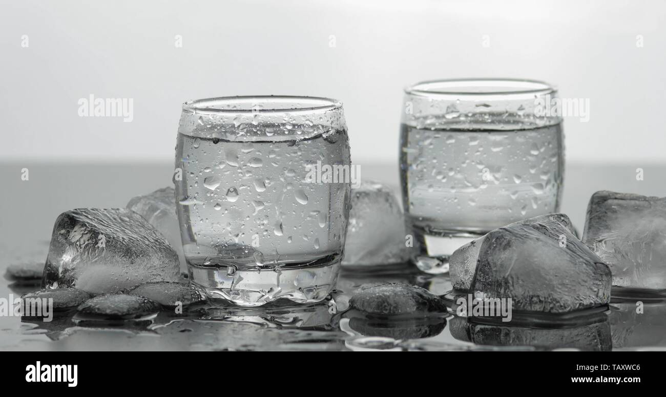 Shots of vodka in glasses. White background with ice cubes. Alcohol
