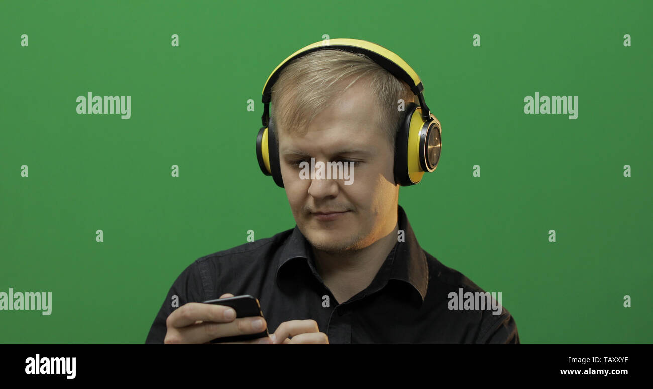 Guy listens to music in wireless yellow headphones. Portrait of