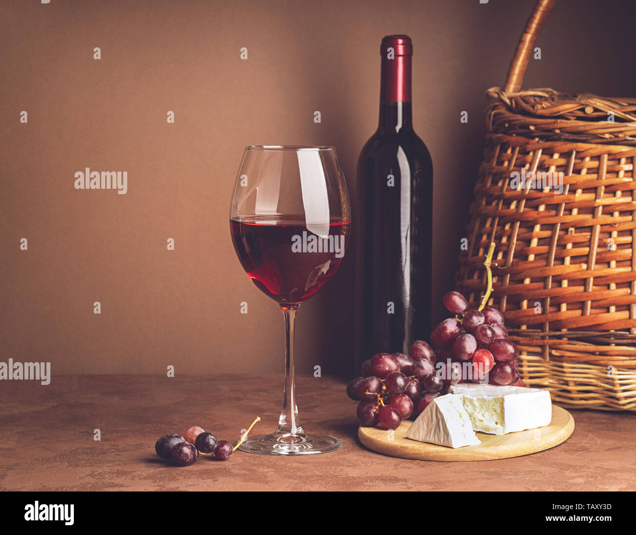 A glass of wine a bunch of red grape cheese slice dark background. Copy space. Still life style dark. Selective focus. Stock Photo