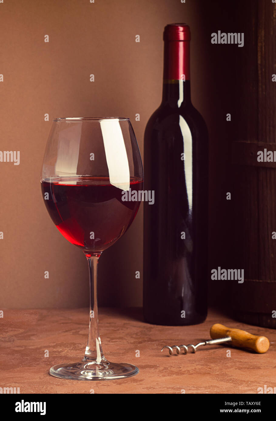 A glass of red wine and a bottle on dark background. Copy space. Still life style dark. Selective focus. Vertical frame. Stock Photo