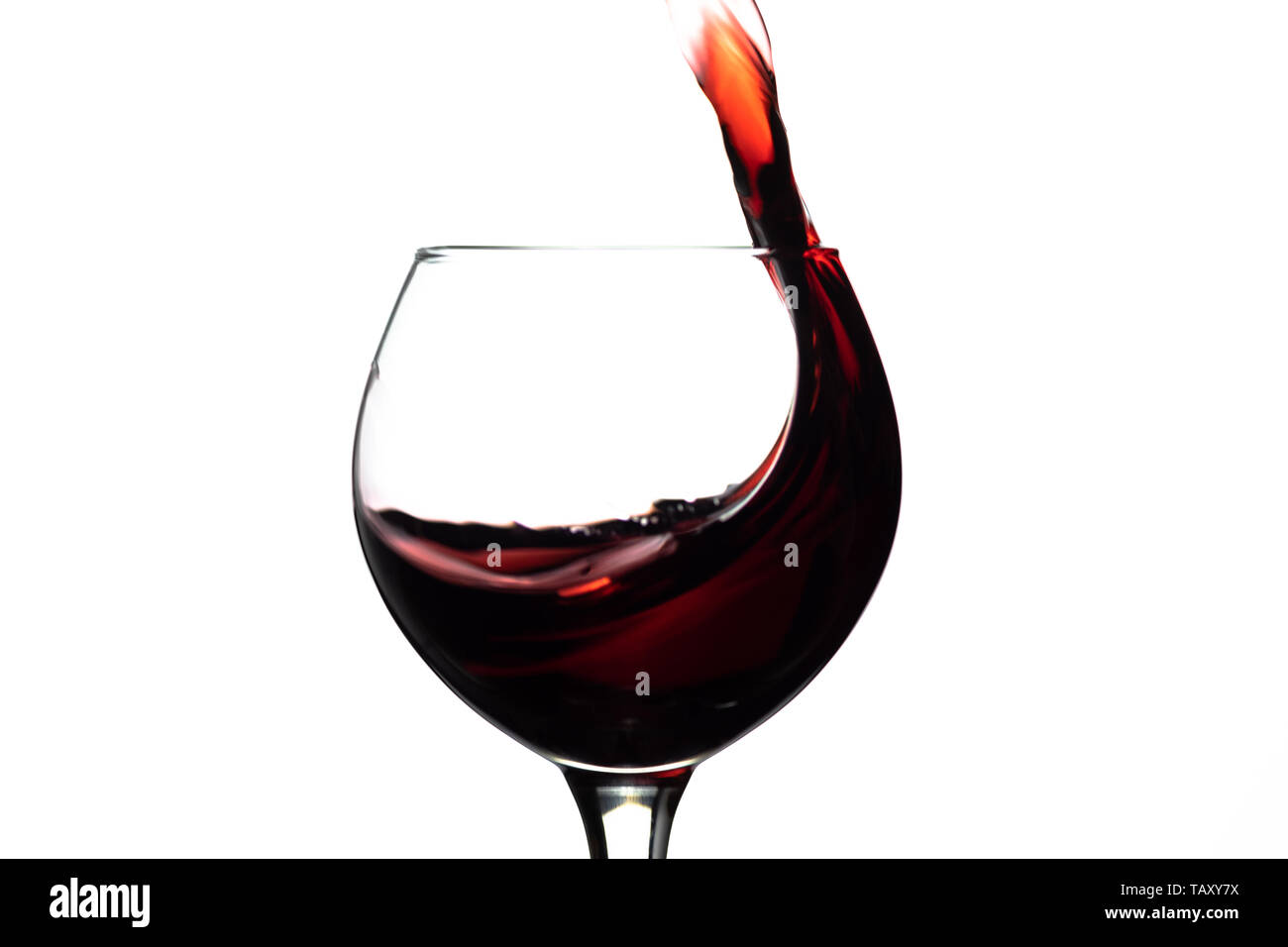 Red wine splash into glass on white background. Stock Photo