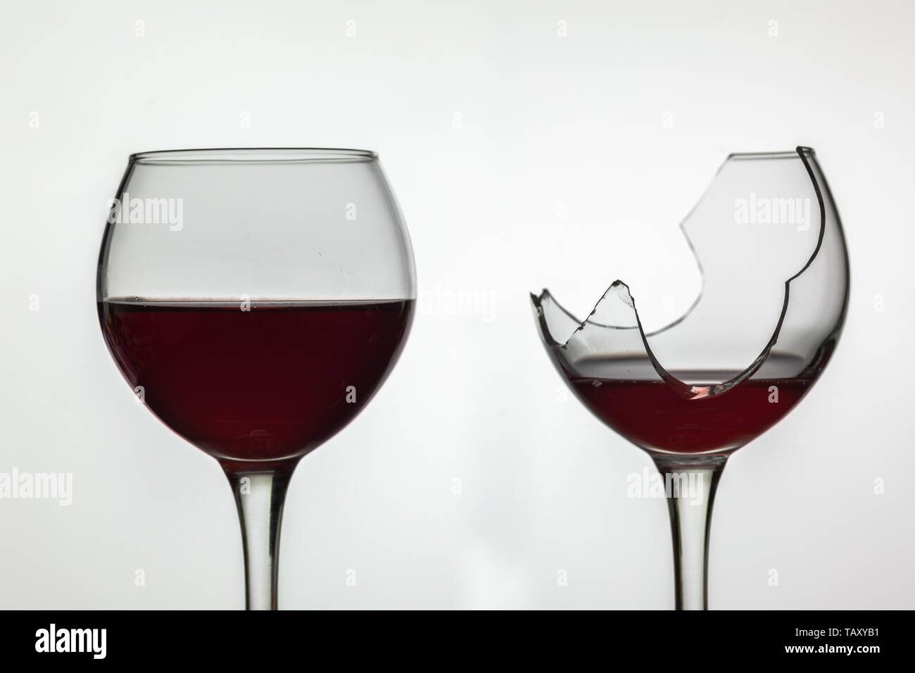 Broken and not broken wine glass with red wine on white background. Stock Photo