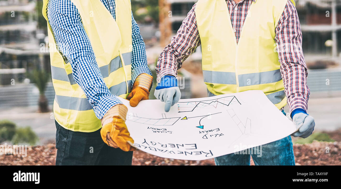 Workers engineers discussing about the new building area - Young builders reading the project in the construction site Stock Photo