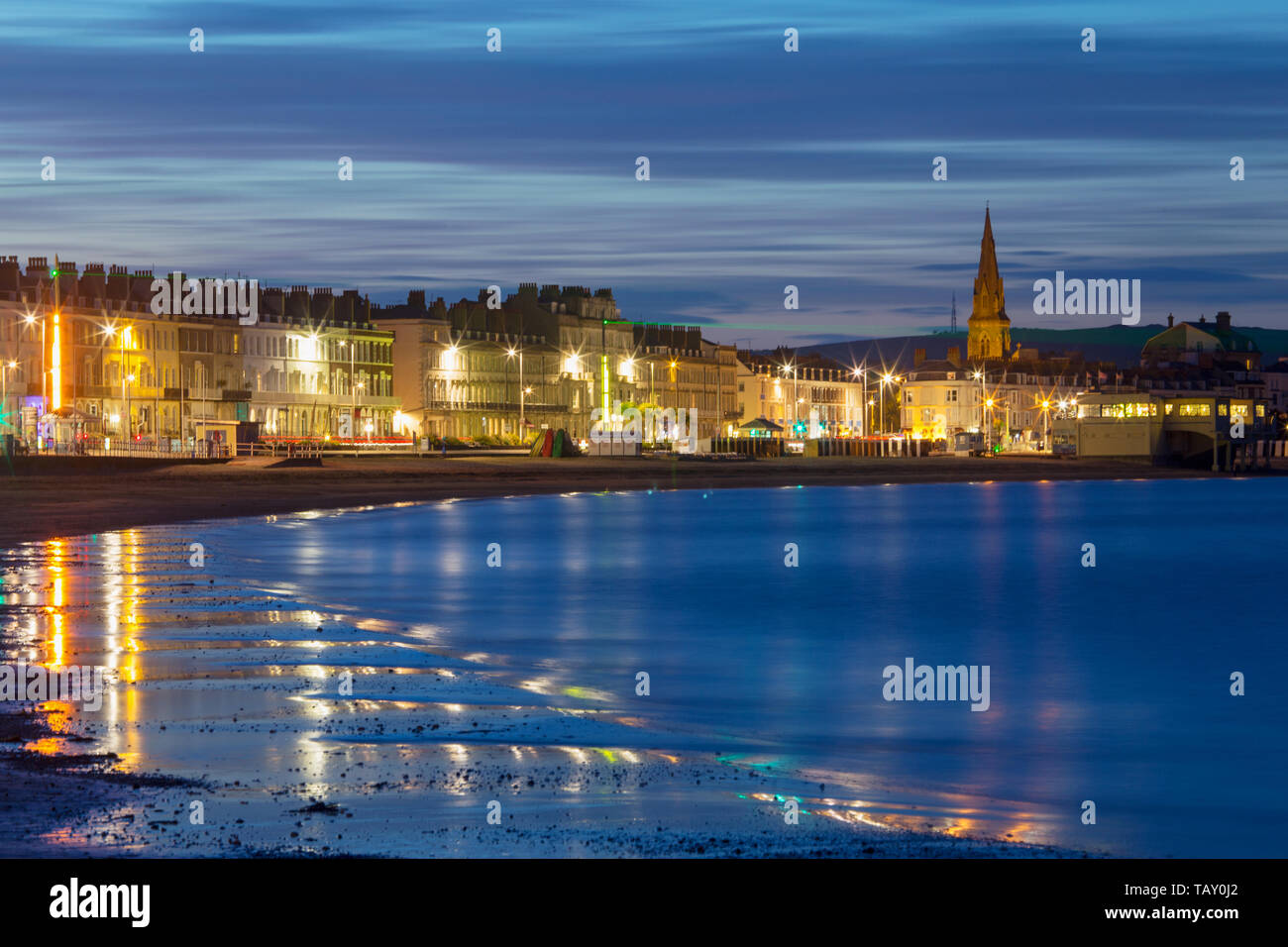 Weymouth seafront Esplanade and St John's Church in Dorset during the blue hour of dusk just before sunset Stock Photo
