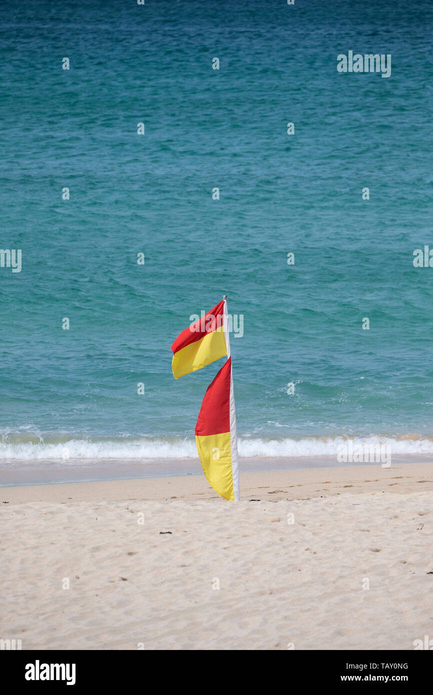 Red and yellow beach warning flags indicating lifeguards are on patrol and an area where it is safe to swim and bathe in the sea Stock Photo